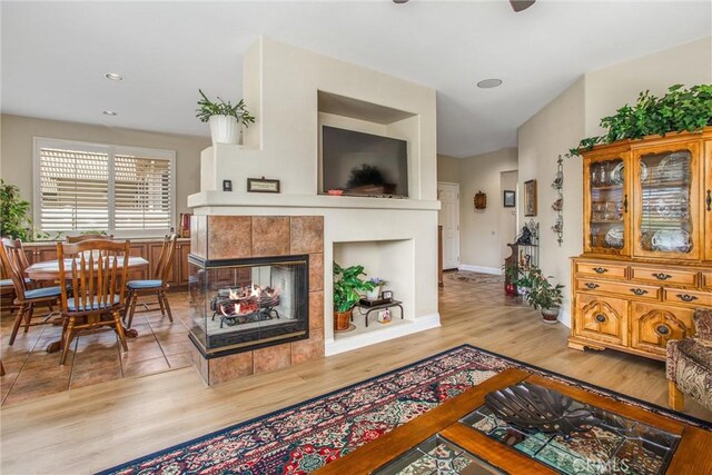 684 Big Spring Dr, Banning, CA 92220 - living room with light wood-type flooring, a tiled fireplace, baseboards, and recessed lighting