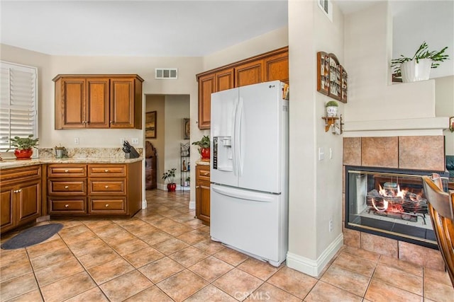684 Big Spring Dr, Banning, CA 92220 - kitchen featuring white refrigerator with ice dispenser, brown cabinets, light stone countertops, and light tile patterned flooring