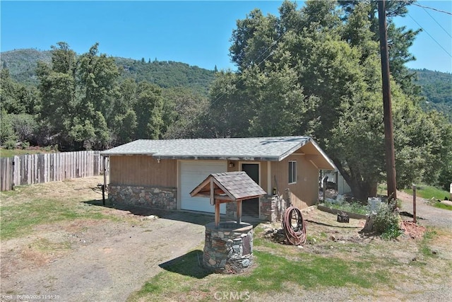3260 E Westfall Rd, Mariposa, CA 95338 - view of front facade with fence, a view of trees, a garage, stone siding, and driveway