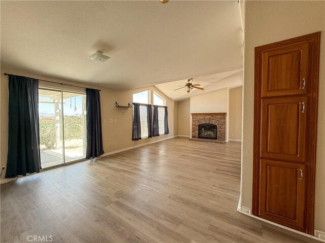 74804 Amboy Rd Unit 29, Palms, CA 92277 - unfurnished living room featuring a ceiling fan, light wood-style floors, a textured ceiling, baseboards, and a stone fireplace