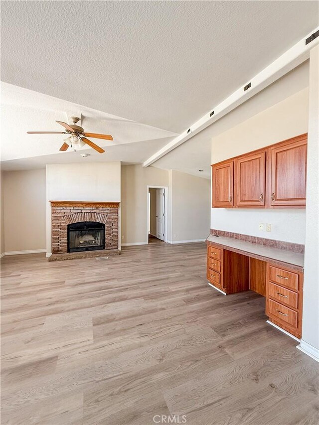 74804 Amboy Rd Unit 29, Palms, CA 92277 - unfurnished living room with light wood-type flooring, a ceiling fan, vaulted ceiling, baseboards, and a textured ceiling