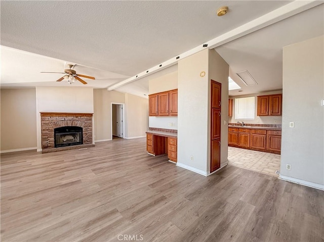 74804 Amboy Rd Unit 29, Palms, CA 92277 - unfurnished living room featuring lofted ceiling, ceiling fan, a sink, light wood finished floors, and a fireplace with raised hearth