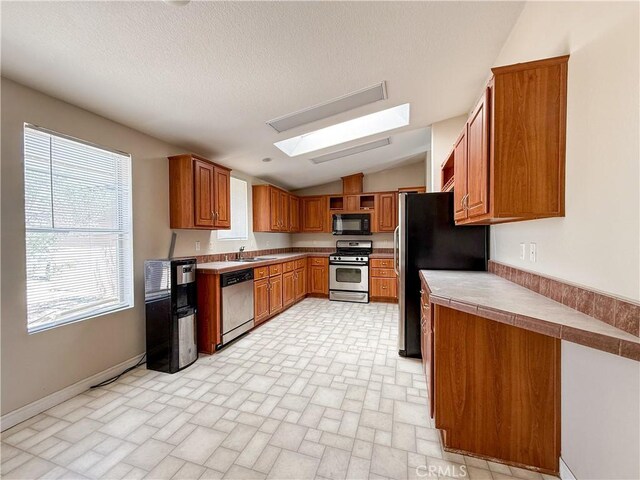 74804 Amboy Rd Unit 29, Palms, CA 92277 - kitchen featuring appliances with stainless steel finishes, vaulted ceiling, a skylight, brown cabinets, and brick patterned floors