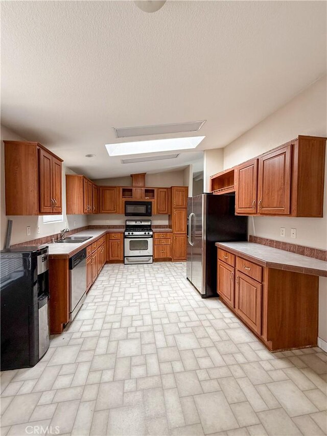 74804 Amboy Rd Unit 29, Palms, CA 92277 - kitchen with appliances with stainless steel finishes, a skylight, a sink, brick patterned flooring, and brown cabinets
