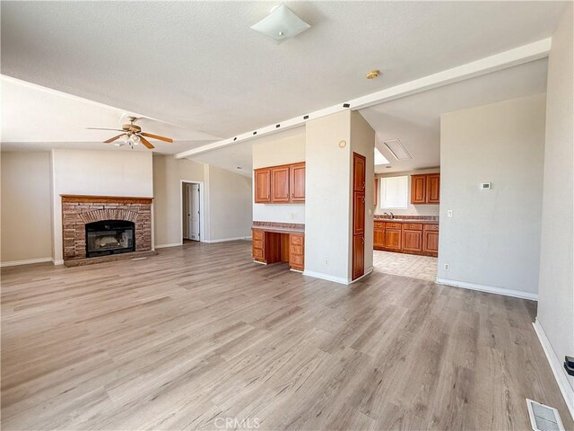 74804 Amboy Rd Unit 29, Palms, CA 92277 - unfurnished living room with vaulted ceiling, ceiling fan, light wood-style flooring, baseboards, and a fireplace