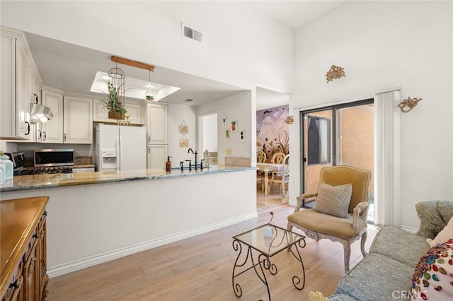 3040 La Paz Ln Unit B, Diamond Bar, CA 91765 - kitchen featuring white refrigerator with ice dispenser, light wood finished floors, exhaust hood, a peninsula, and light stone counters