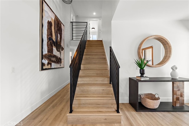 stairway with wood finished floors, baseboards, and recessed lighting