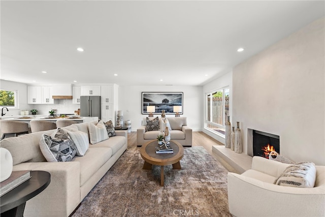 living area featuring recessed lighting, a lit fireplace, and light wood finished floors