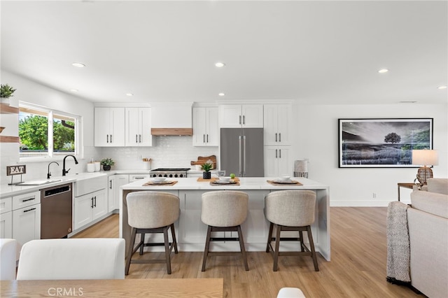 kitchen with appliances with stainless steel finishes, white cabinetry, a center island, decorative backsplash, and a breakfast bar