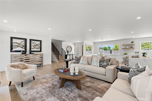 living area with stairway, recessed lighting, light wood-type flooring, and baseboards