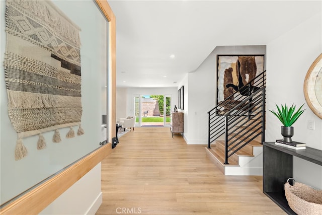 hallway with light wood finished floors, stairway, baseboards, and recessed lighting