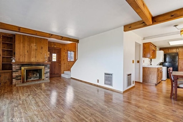 15440 Shasta Way, Pine Mountain Club, CA 93225 - unfurnished living room with beam ceiling, wood finished floors, a fireplace with raised hearth, heating unit, and stairs