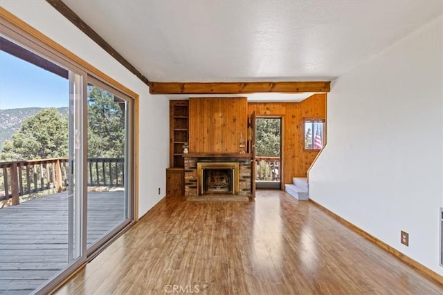 15440 Shasta Way, Pine Mountain Club, CA 93225 - unfurnished living room with beamed ceiling, wood finished floors, wood walls, and a fireplace with raised hearth