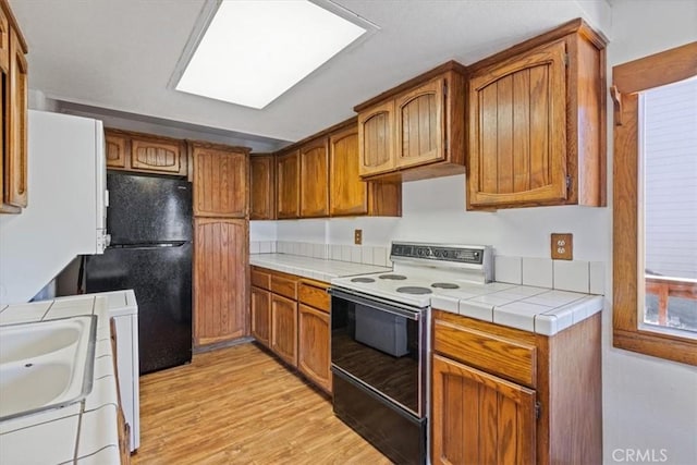 15440 Shasta Way, Pine Mountain Club, CA 93225 - kitchen with range with electric cooktop, freestanding refrigerator, light wood-type flooring, tile countertops, and brown cabinets