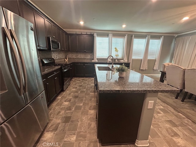 16654 Emerson Ln, Fontana, CA 92336 - kitchen featuring appliances with stainless steel finishes, dark stone countertops, backsplash, dark brown cabinetry, and a center island with sink