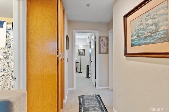 hallway featuring light carpet and baseboards