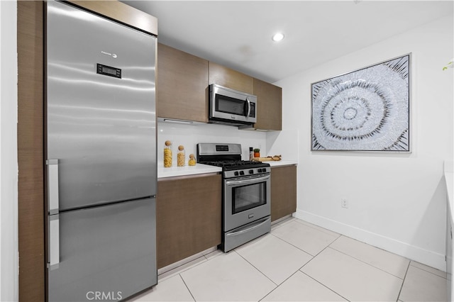 kitchen featuring appliances with stainless steel finishes, light countertops, baseboards, light tile patterned floors, and recessed lighting