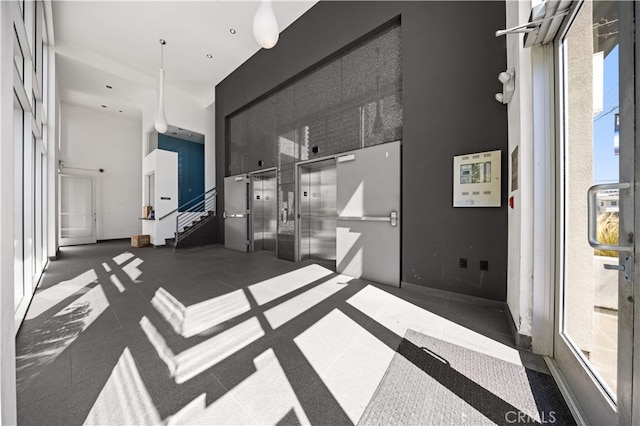 tiled spare room featuring a high ceiling, elevator, and stairway