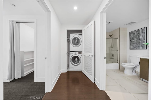 clothes washing area with stacked washer / drying machine, baseboards, and recessed lighting