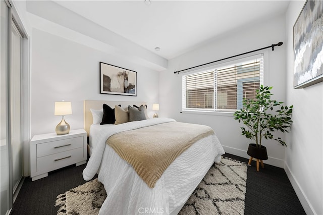 bedroom featuring dark carpet and baseboards