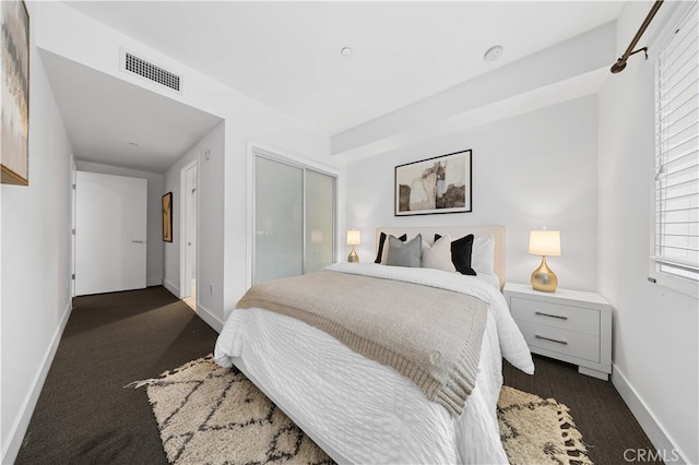 bedroom featuring dark colored carpet, a closet, and baseboards