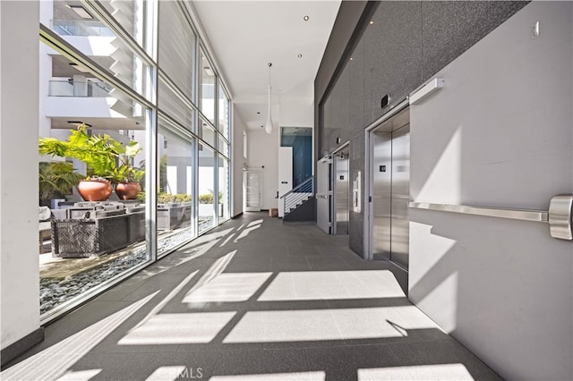 hallway featuring a towering ceiling, stairs, and elevator