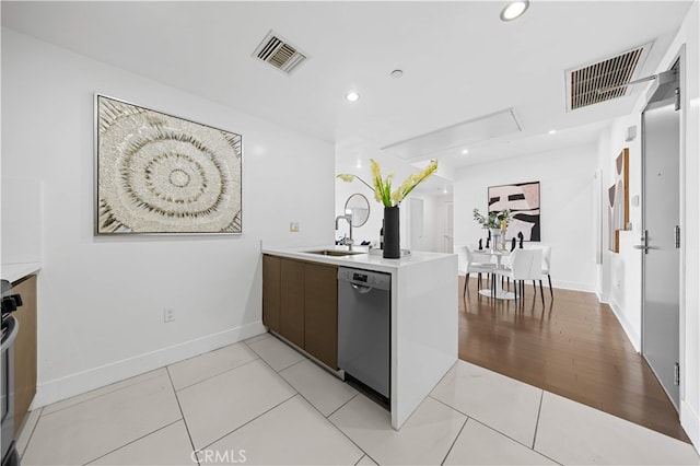 kitchen featuring stainless steel dishwasher, a sink, light countertops, a peninsula, and modern cabinets