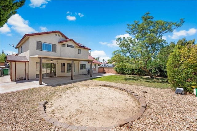 back of house featuring ceiling fan, stucco siding, roof mounted solar panels, a patio area, and fence