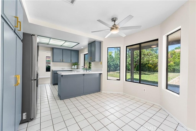 kitchen with a peninsula, gray cabinets, light countertops, and light tile patterned floors