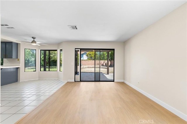 empty room featuring a ceiling fan, baseboards, and light wood-style floors