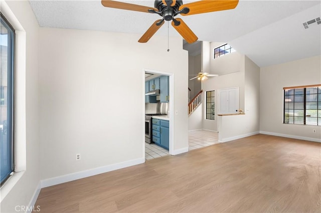 unfurnished living room with a ceiling fan, light wood-style floors, vaulted ceiling, and baseboards