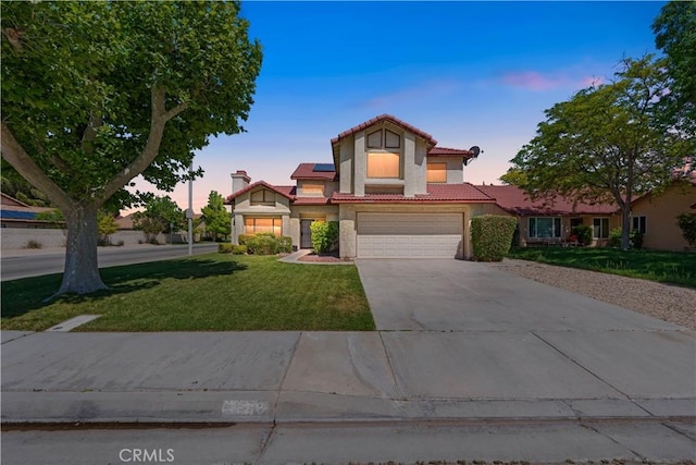 view of front of house featuring a tiled roof, an attached garage, roof mounted solar panels, a yard, and driveway