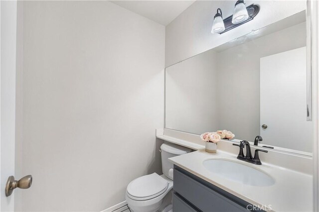 bathroom featuring toilet, vanity, and baseboards
