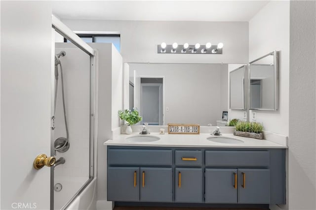 full bath featuring double vanity and combined bath / shower with glass door