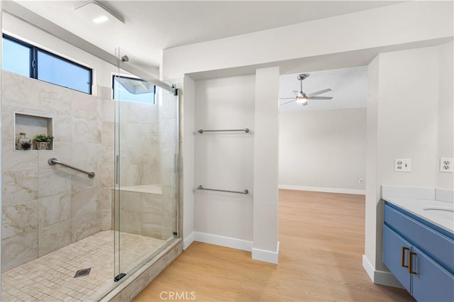bathroom featuring a ceiling fan, a shower stall, baseboards, and wood finished floors