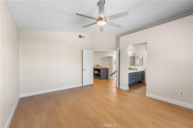 unfurnished bedroom with light wood-type flooring, baseboards, a textured ceiling, and ensuite bathroom