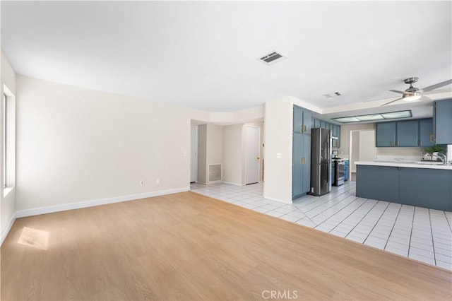 unfurnished living room featuring ceiling fan, light wood-style floors, and baseboards