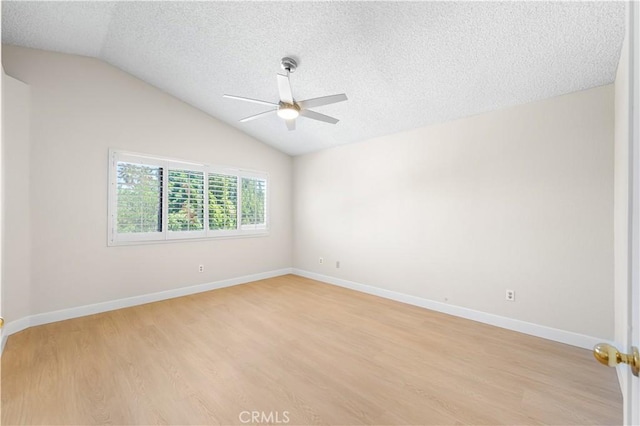 empty room with ceiling fan, vaulted ceiling, light wood-style floors, a textured ceiling, and baseboards