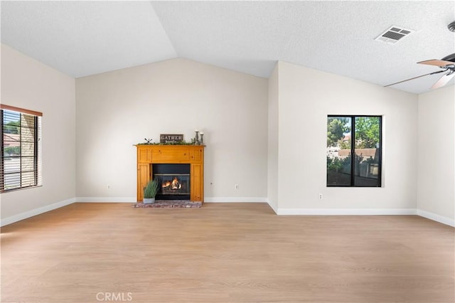 unfurnished living room featuring lofted ceiling, light wood-type flooring, a glass covered fireplace, ceiling fan, and baseboards