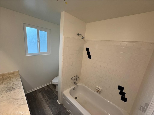 bathroom featuring wood finished floors, toilet, tub / shower combination, and baseboards