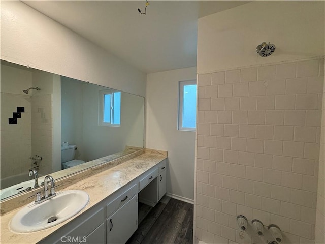 bathroom with wood finished floors, toilet, vanity, bathtub / shower combination, and baseboards