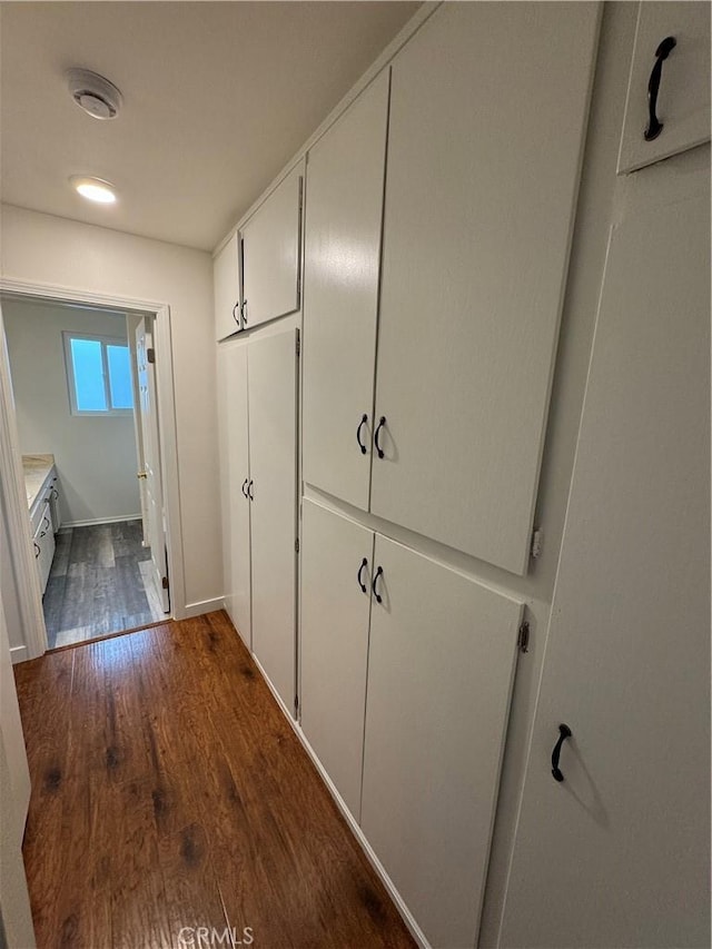 hallway featuring dark wood finished floors and baseboards