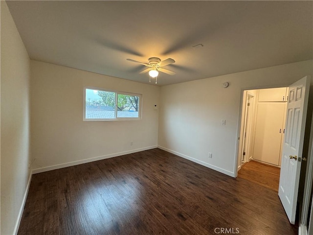 empty room with dark wood-style flooring, baseboards, and ceiling fan