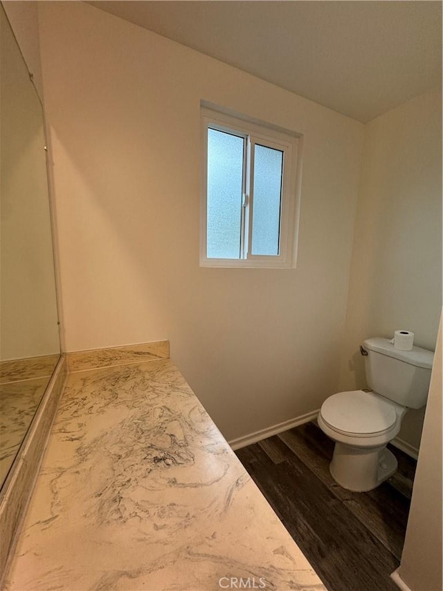 bathroom featuring wood finished floors, toilet, and baseboards