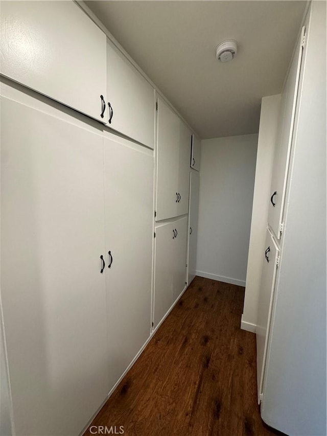 hallway with dark wood-type flooring and baseboards
