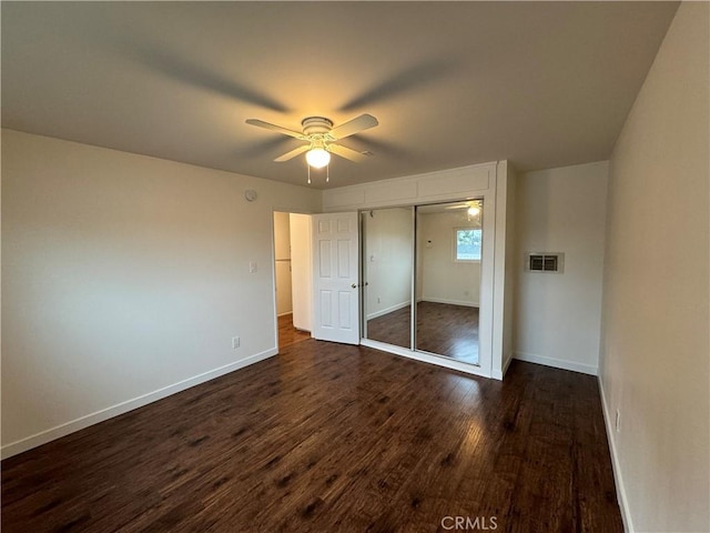 unfurnished bedroom featuring dark wood finished floors, baseboards, a closet, and a ceiling fan
