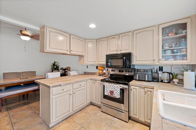 3470 Peach Tree Way, Oceanside, CA 92058 - kitchen featuring black microwave, stainless steel electric range, a peninsula, light tile patterned floors, and cream cabinetry