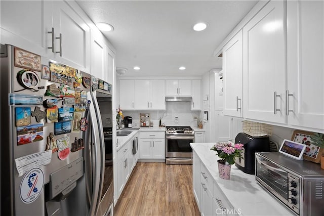 1118 Kwis Ave, Hacienda Heights, CA 91745 - kitchen featuring stainless steel appliances, light wood-type flooring, white cabinetry, under cabinet range hood, and light stone countertops