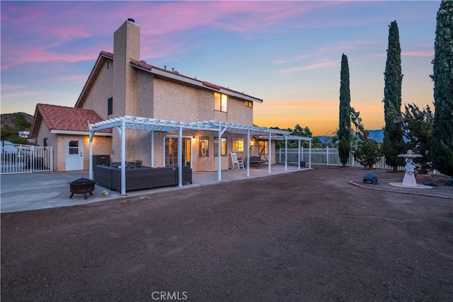 33693 Cattle Creek Rd, Acton, CA 93510 - back of property at dusk with a pergola, an outdoor fire pit, a fenced backyard, a patio, and stucco siding