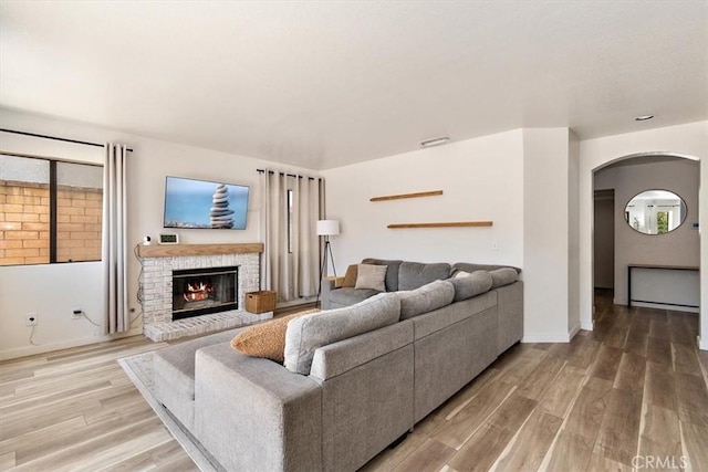 6517 Via Del Prado, Chino Hills, CA 91709 - living area featuring arched walkways, light wood-type flooring, a brick fireplace, and baseboards